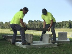 two men lifting a slab of concrete to build a bench