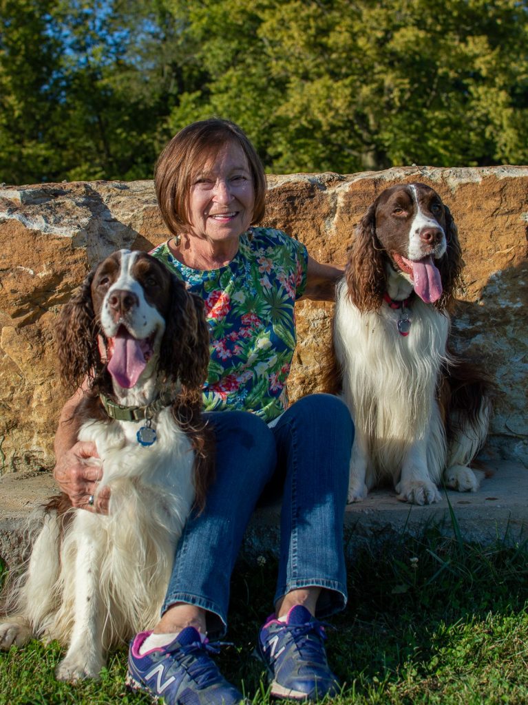 woman sitting between 2 dogs